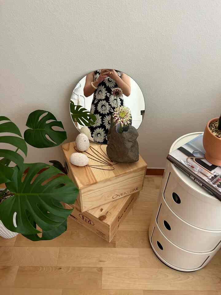 白い壁とナチュラルな木目調の床、コーナーに置かれた白いメタル収納ユニットと植物のある雰囲気のあるインテリア