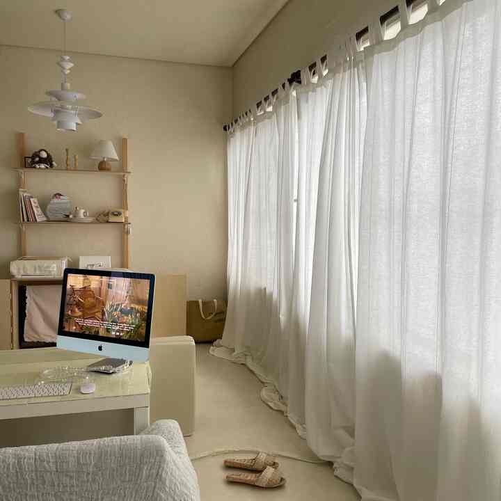 Bright living room with soft white and beige tones, featuring large windows with white cotton curtains and wooden shelving, cozy atmosphere connected to kids' room