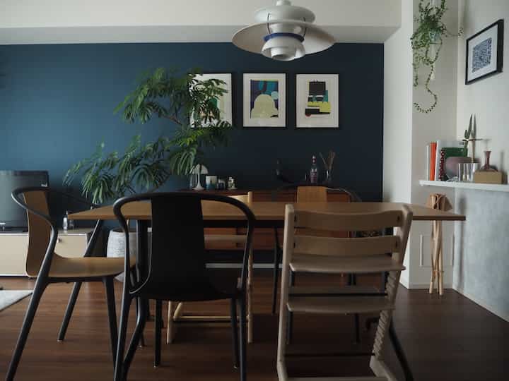 ネイビーのアクセント壁と木目調のダイニングテーブルが置かれた4人家族向けのリビング・ダイニングルーム