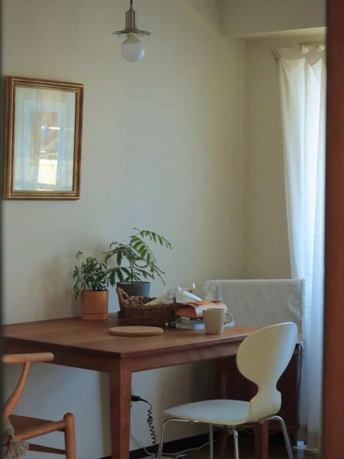 白と茶色のトーンが特徴的なカフェ風のリビング、食卓と椅子が配置された落ち着いた空間