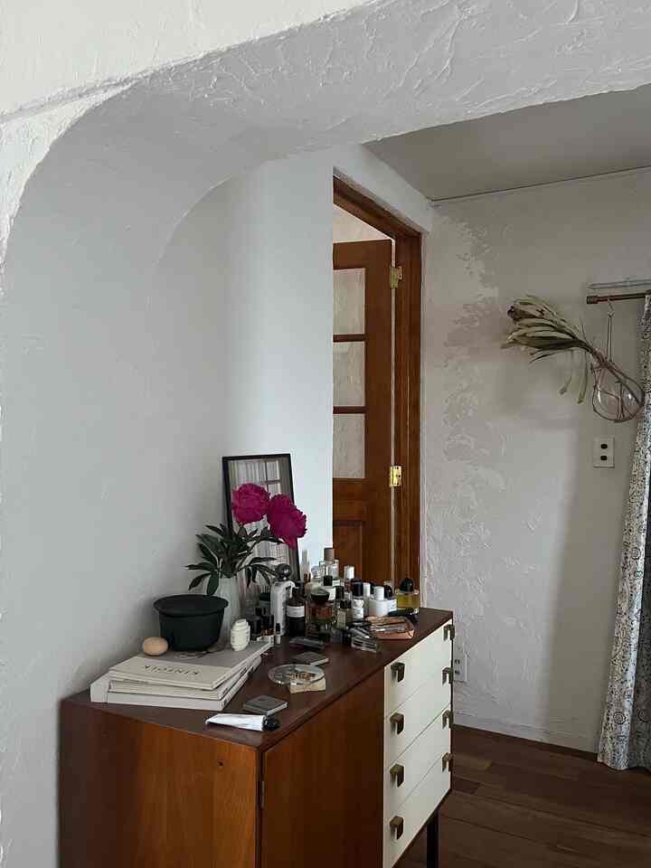 白い壁と茶色の木製キャビネットが置かれた狭い玄関、ヴィンテージ家具が印象的な雰囲気のあるインテリア