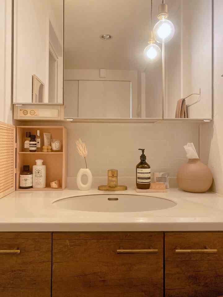 ナチュラルモダンなバスルーム、木目調のキャビネットと白い洗面台が配置された雰囲気のあるインテリア