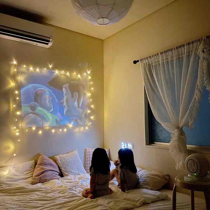 ベージュ調の寝室、子供二人がホームシネマ用プロジェクター映像を見ている雰囲気のあるインテリア