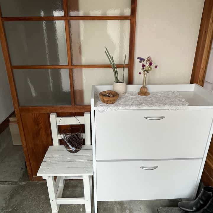 White shoe cabinet and wooden frame in folk house style entrance, cozy traditional atmosphere