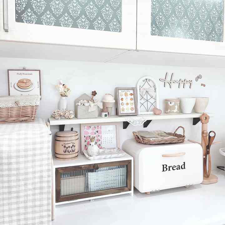 Natural kitchen space in white and brown tones featuring a bread case, picture frames, and smart storage ideas with coordinated horizontal lines