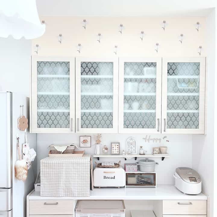 Bright white-toned kitchen featuring beige floral wallpaper, storage bread case, and neat décor highlighting Korean interior style