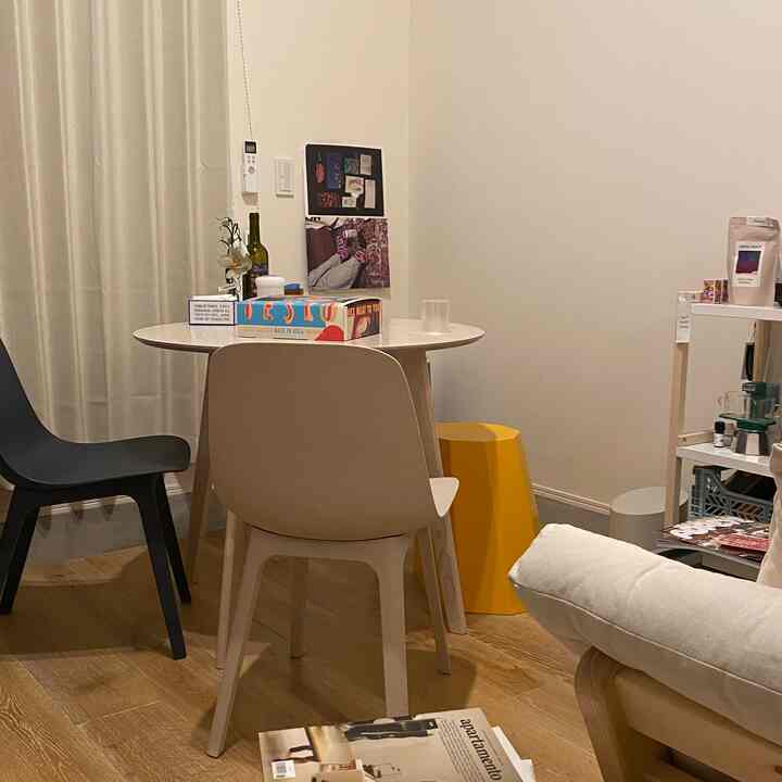 白い壁と木目調の床が印象的なナチュラルモダンスタイルのダイニングルーム。丸いダイニングテーブルと三脚の椅子が配置された空間