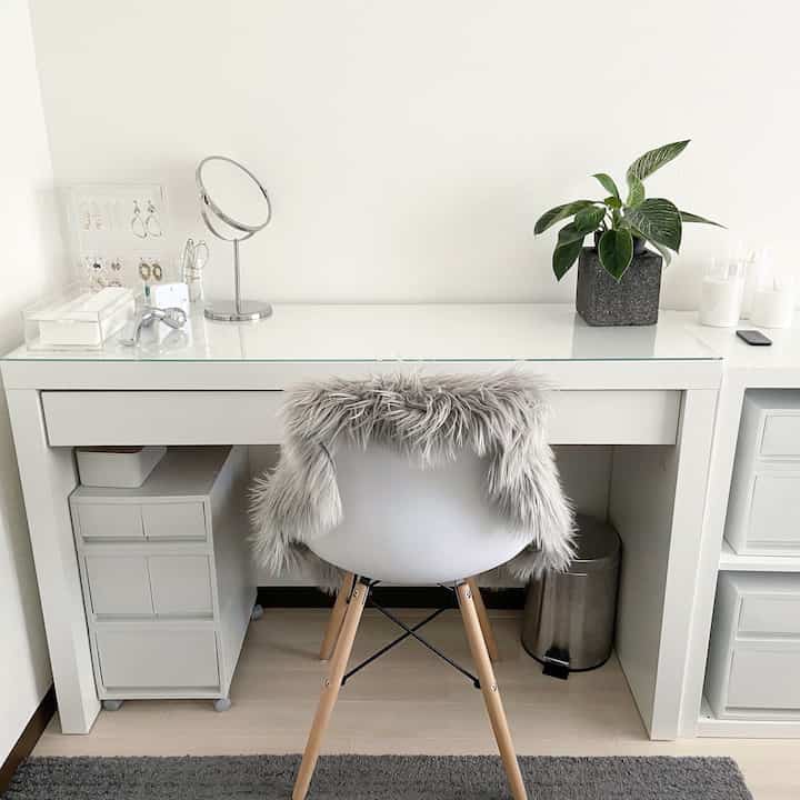 Bright white-toned single household room featuring a vanity desk with natural wood legs and a green plant for a fresh atmosphere