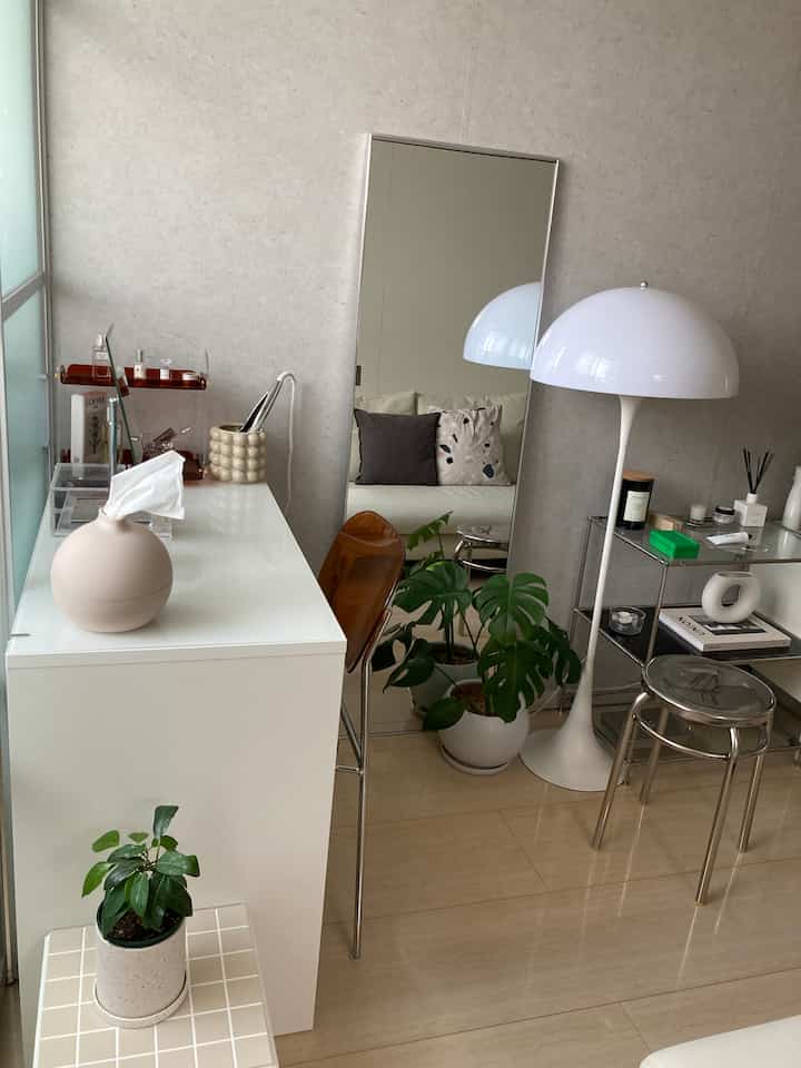 White and beige toned small room with a large full-length mirror and modern furniture arranged around a clean vanity area