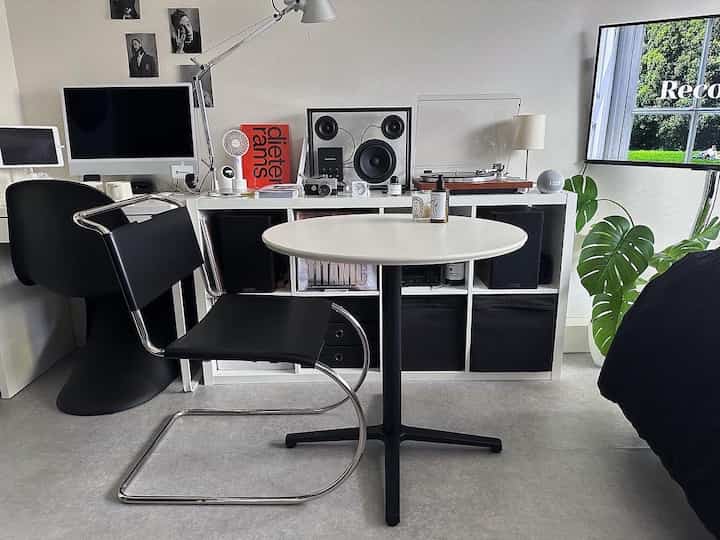 Modern single household space in black and white tones featuring chrome frame chair and round table with a clean interior