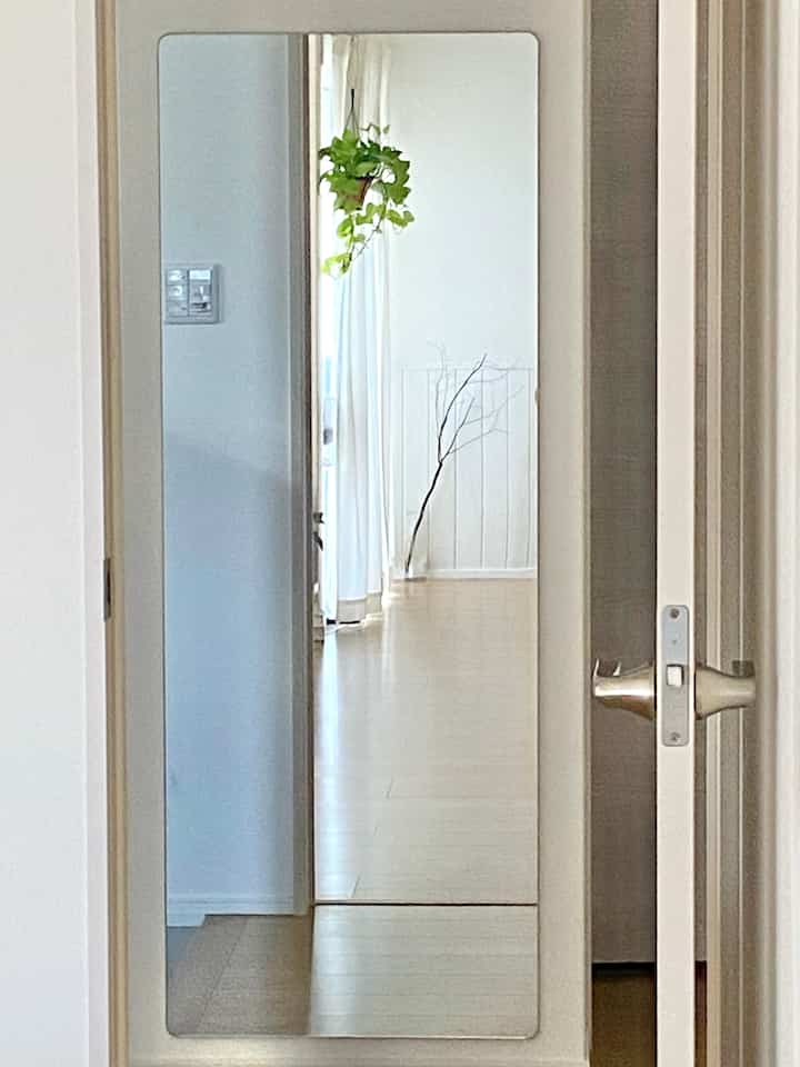 Light natural tone entrance with white walls, featuring a large frameless mirror creating a spacious atmosphere