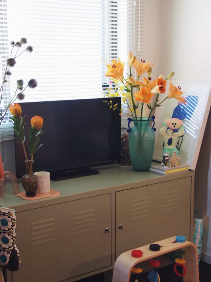 ベージュのキャビネットの上にテレビとさまざまな花瓶が置かれたリビング、ナチュラルな色調で落ち着いた雰囲気のインテリア。