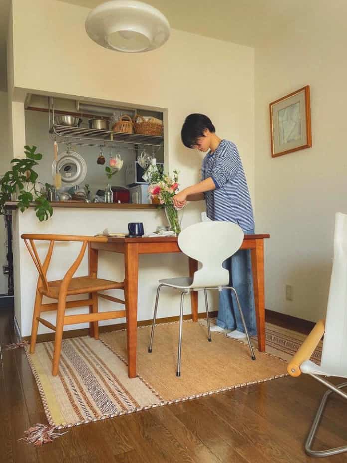 ナチュラルな木目調と白を基調としたダイニング、中央に配置された食卓と椅子、花瓶が置かれた雰囲気のある空間