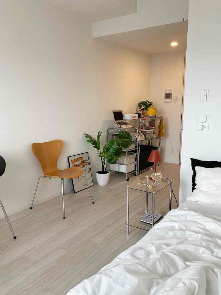 White and natural toned bedroom featuring bed, plant, and long narrow room layout