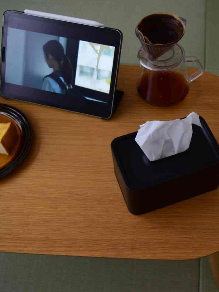 ナチュラルな木目調のテーブルに黒のティッシュケースとドリップコーヒーセット、タブレット端末が配置された雰囲気のあるキッチン