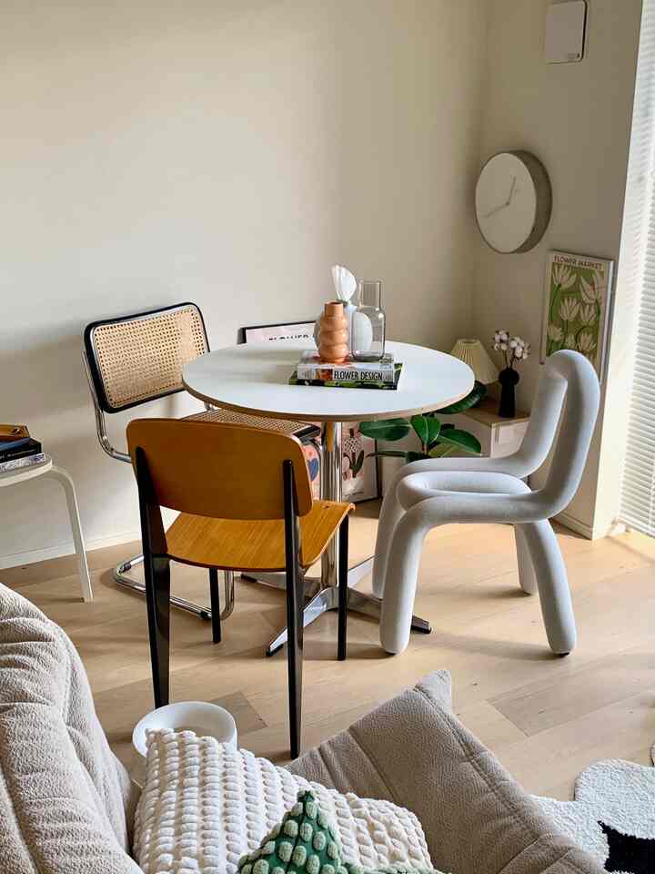 Natural-toned dining room featuring various style chairs and a white round dining table creating a cozy atmosphere