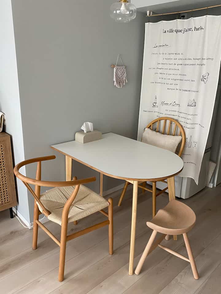 グレーの壁とナチュラルウッド調家具が配置された二人暮らし用カフェ風のダイニングスペース