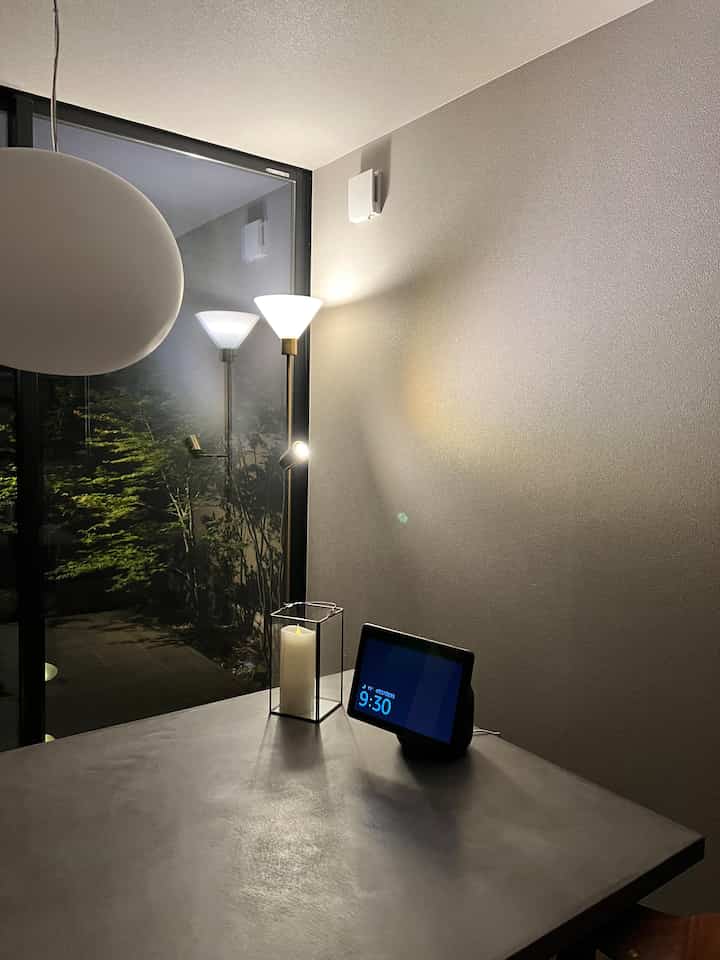 グレー調のダイニング、コンクリート風のテーブルとフロアランプ、LEDキャンドルが配置され、落ち着いた雰囲気のあるインテリア