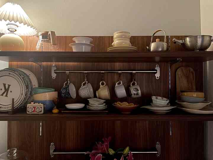 ナチュラルな木目調の棚に白を基調とした様々な食器が整然と配置されたキッチンのインテリア