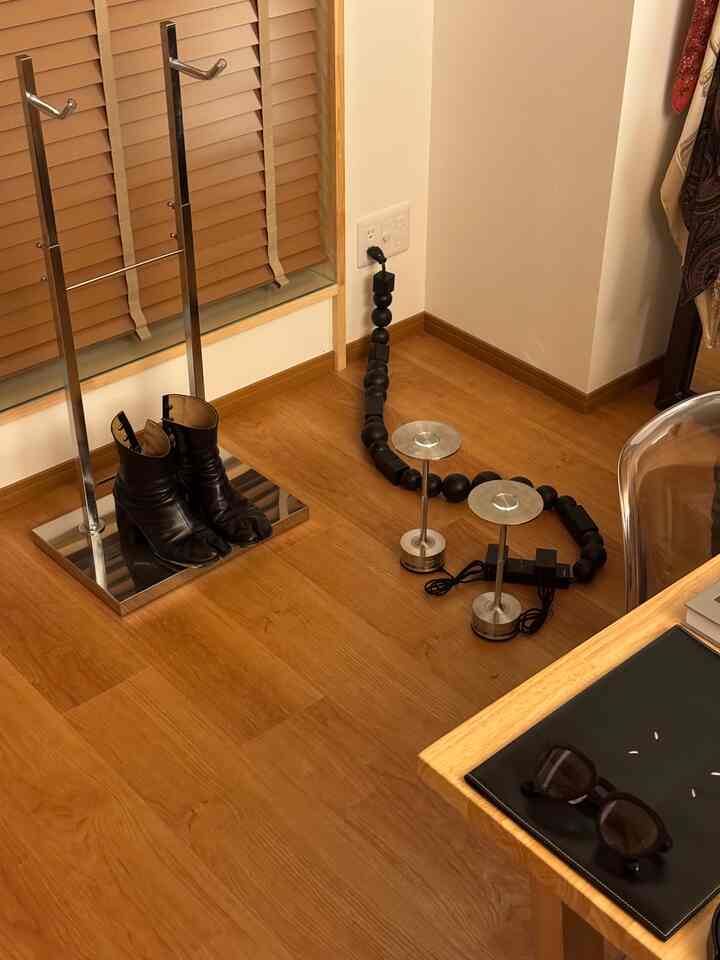 木目調の床の角に黒い革のブーツとマルチプラグケーブルが配置されたモダンな空間