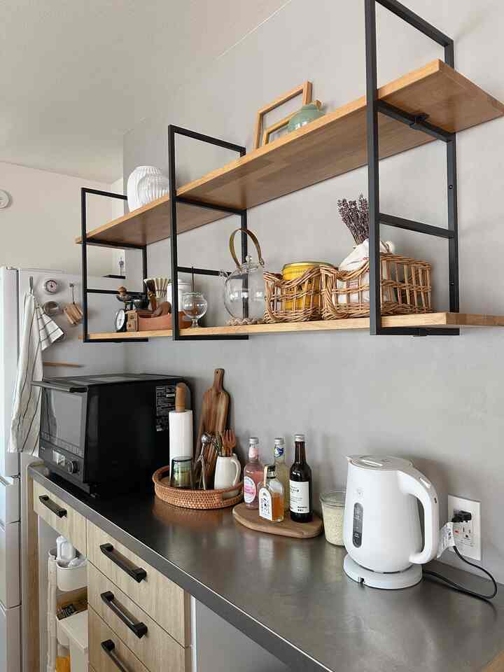 ベージュとブラックの色調のキッチン、木製の棚と電気ケトルが置かれた整理された空間