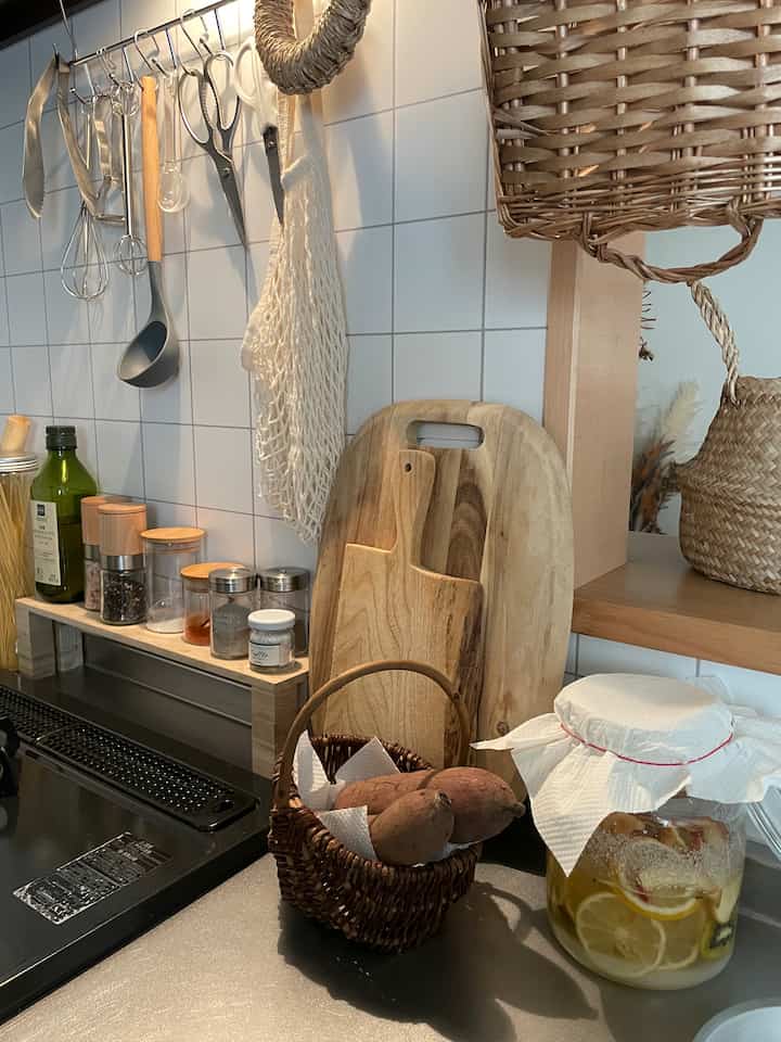 ナチュラルな色調のキッチン、木製まな板とバスケットが配置された落ち着いた雰囲気の空間