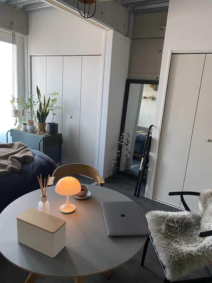 Light gray and wood tone dining room featuring a round table, chairs, and large mirror in a simple setting