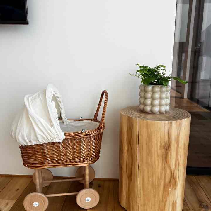 Natural-toned kids' room corner featuring a wooden log stool topped with a bubbly beige planter containing a green plant