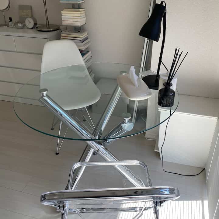 A clean, modern dining room with transparent glass table and white chair under natural light