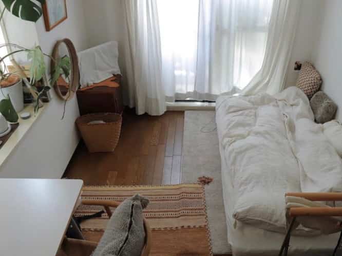 Soft white and natural wood tones characterize this 18㎡ studio apartment featuring a sofa bed and natural decor elements for a cozy atmosphere