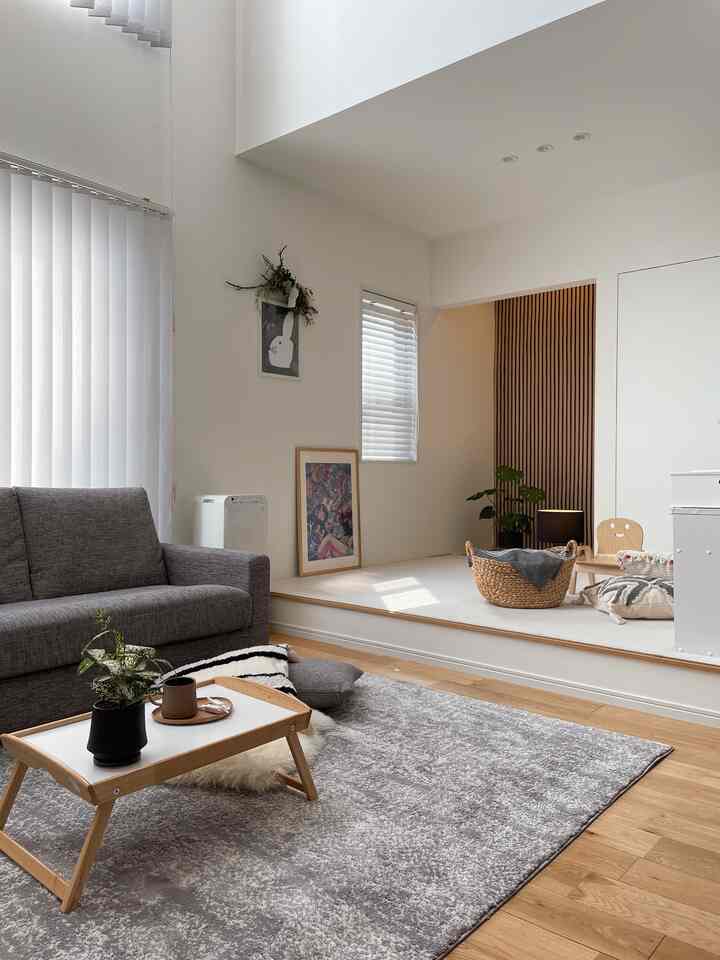 グレーのソファと木目調のコーヒーテーブルが配置された、白とグレーのモノトーンのナチュラルなリビング