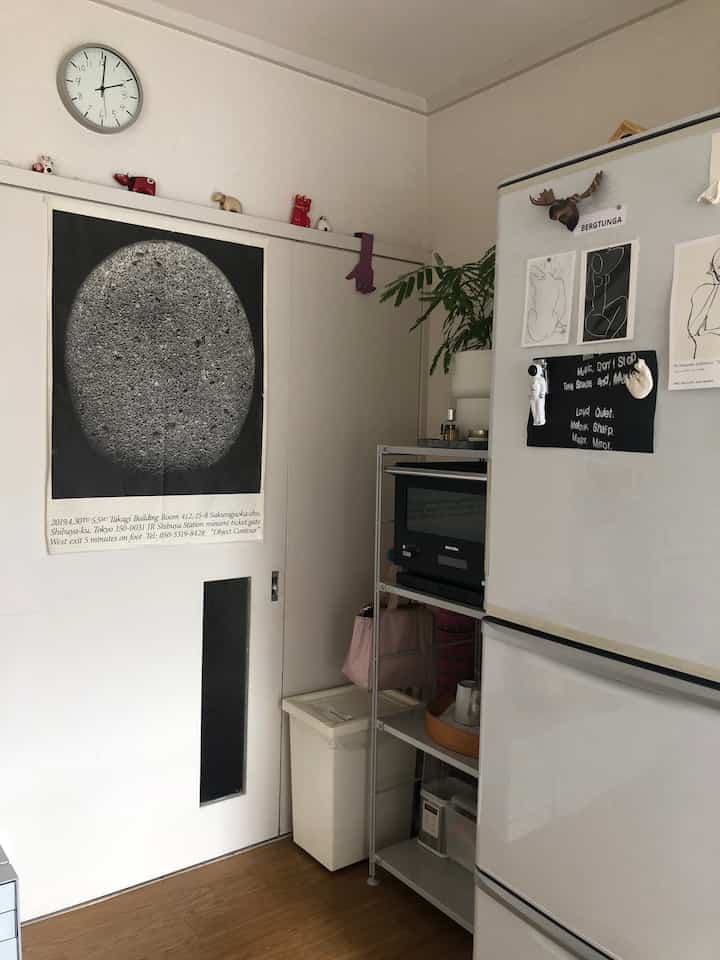 Modern kitchen with white walls and door featuring a black poster and black appliances