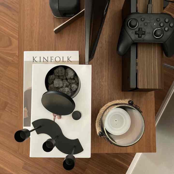 ブラウンの木目調コンソールテーブルに黒いゲームコントローラーとキャンドル、モダンで落ち着いたアクセサリーが配置された雰囲気のあるインテリア