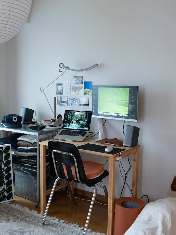 ナチュラルカラーのワークスペース、折りたたみテーブルとオフィスチェアが置かれたシンプルでコンパクトな空間