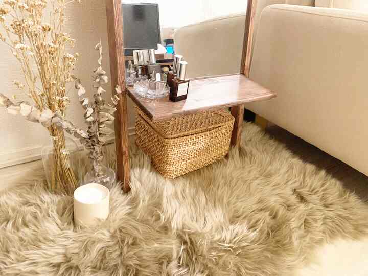 ベージュとブラウンのトーンが特徴のリビングコーナー、ラタンバスケットと鏡が配置されたナチュラルモダンな空間