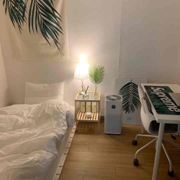 Minimal bedroom in white and wood tones featuring a bed, nightstand, desk, and office chair with a natural cozy atmosphere