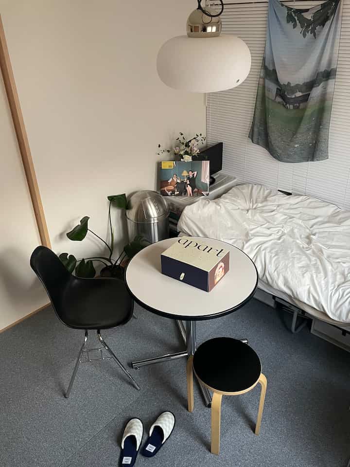 Compact single household room with white walls and bedding, featuring black furniture pieces