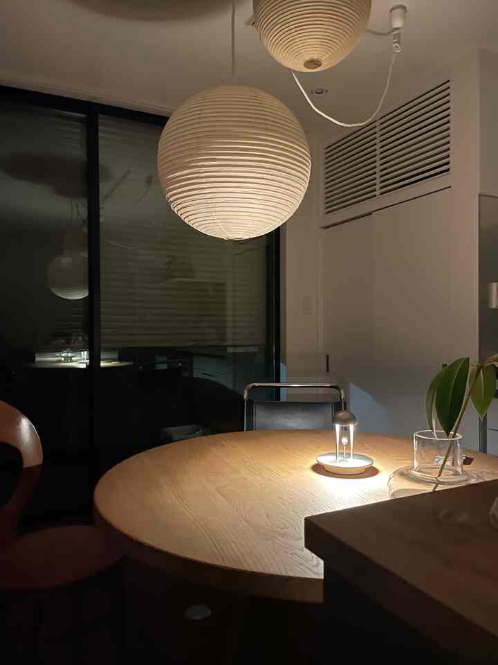 柔らかな白い間接照明と温かみのあるブラウンの丸テーブルが配置された落ち着いたダイニング空間