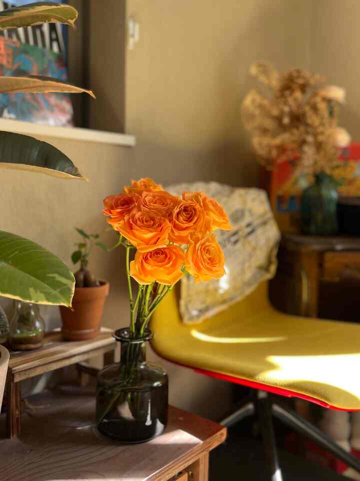 ナチュラルカラーの壁と木製家具、黄色いオフィスチェアが配置された落ち着いたリビングコーナー