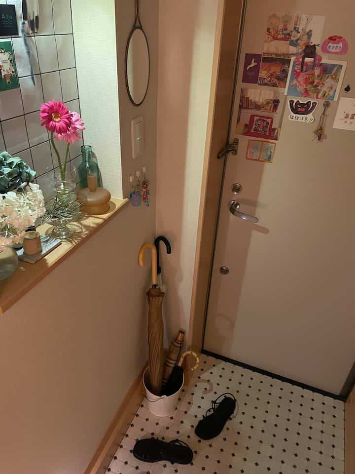 明るいウッドトーンとホワイトの玄関、花瓶と傘立てが配置された雰囲気のある空間