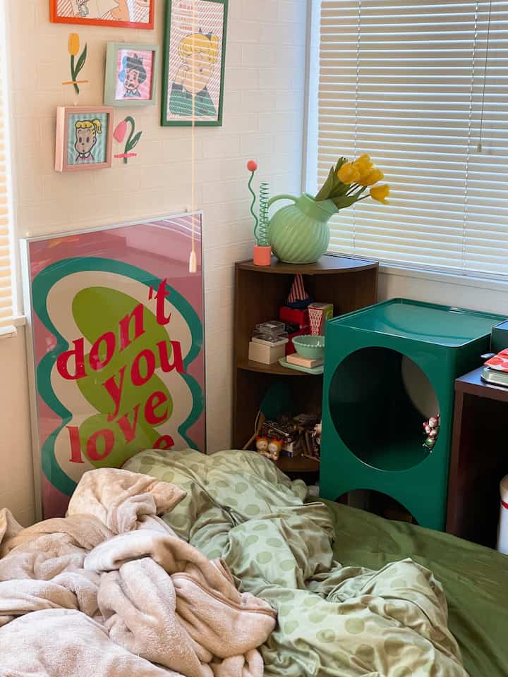 グリーンとイエローの色調の寝室、ドット柄の掛け布団カバーとレトロな額入りアートが配置された印象的な空間