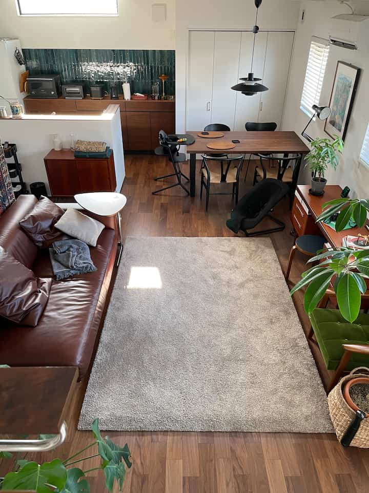 ウッドトーンとホワイトのリビング・ダイニングルーム、ブラウンレザーソファと木製のダイニングテーブルが配置されたモダンなインテリア