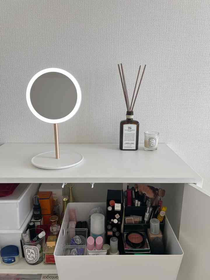 White-toned vanity featuring a round LED-lit mirror and fragrance diffuser, creating a neat and compact makeup area