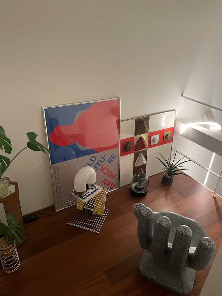 Natural wood-tone floor corner space featuring posters and plants with a cozy atmosphere