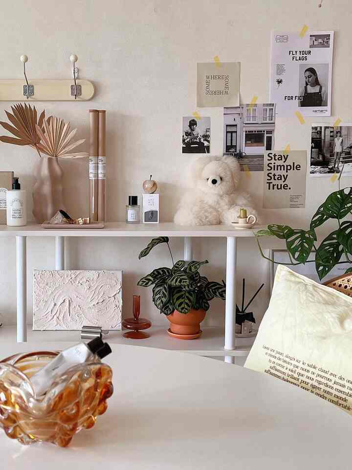 ナチュラルな色調のリビングスペース、壁に飾られたアートと棚の上の植物が印象的な雰囲気を作る