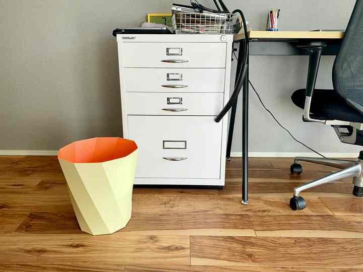 Compact home office space with white filing cabinet and black office chair on natural wood tone floor