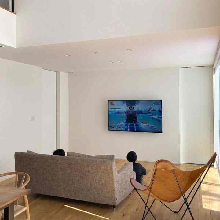 白と木目調のリビング、グレーのソファとブラウンのバタフライチェアが配置されたモダンで清潔感のある空間