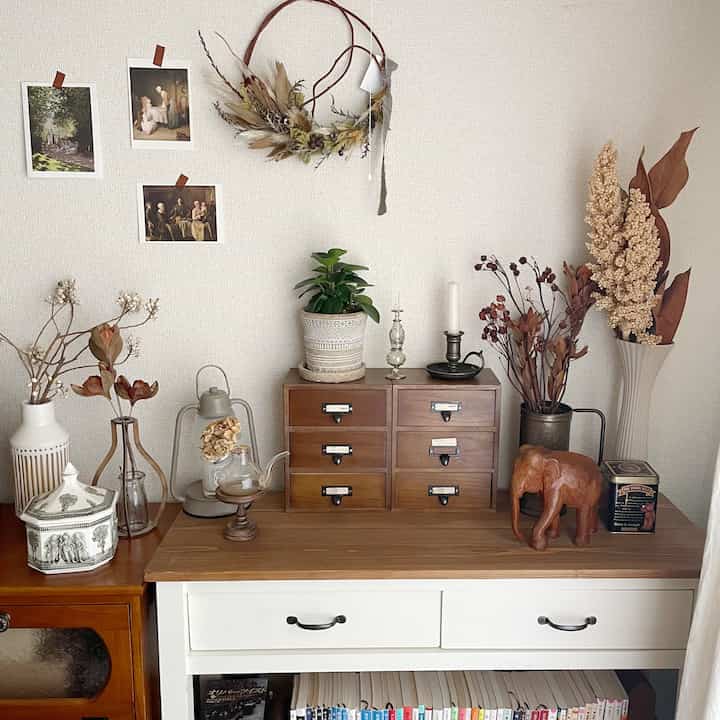 ブラウンとホワイトトーンのリビングスペース、アンティークの収納棚と植物、インテリア小物が配置された自然な雰囲気のインテリア