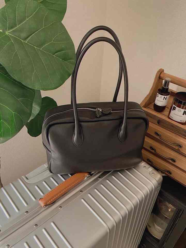 シルバーのアルミボディースーツケースの上に黒い革のバッグが置かれた落ち着いた収納スペース