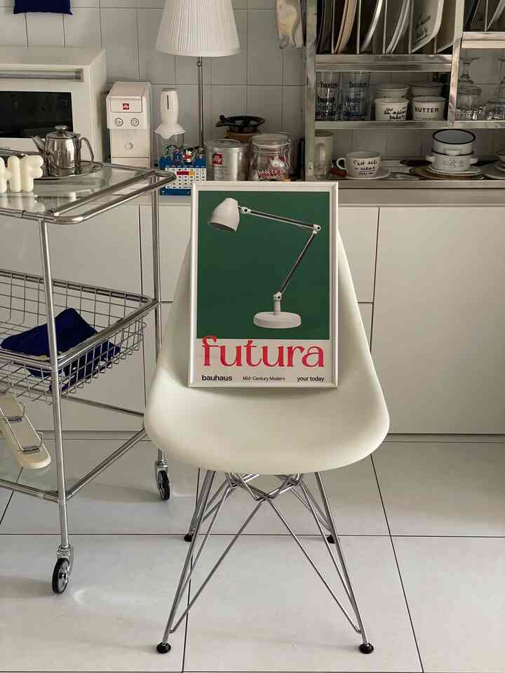 Natural and white-toned kitchen space featuring a central Eames chair with a framed poster, showcasing a clean modern interior